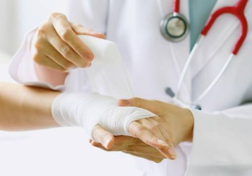 Close-up of female doctor with stethoscope bandaging hand of patient. (Selective Focus)