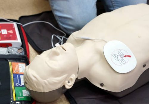 Basic life support simulation scenario for medical students on a dummy with an automatic external defibrillator during cardiopulmonary resuscitation.